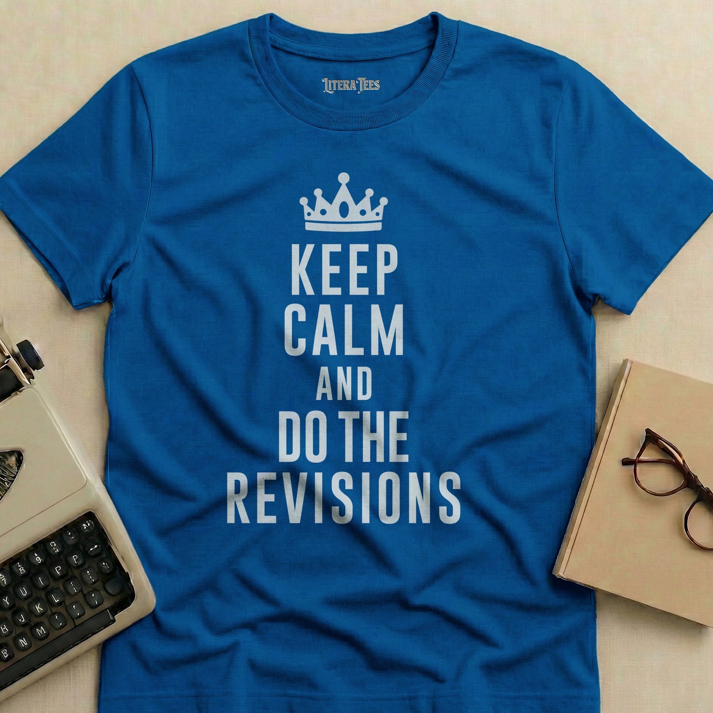 Blue t-shirt with white text "KEEP CALM AND DO THE REVISIONS" and a crown.