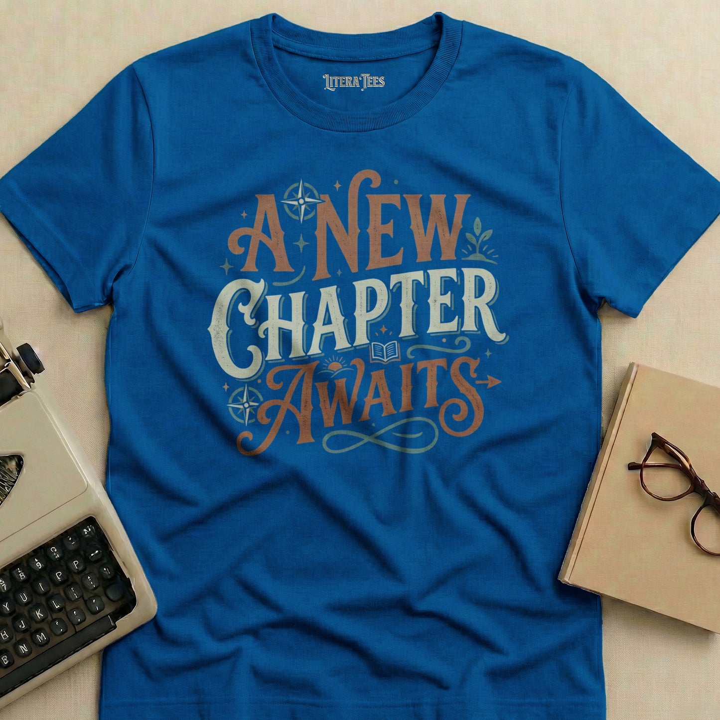 Blue t-shirt with "A NEW CHAPTER AWAITS" text in distressed serif font.