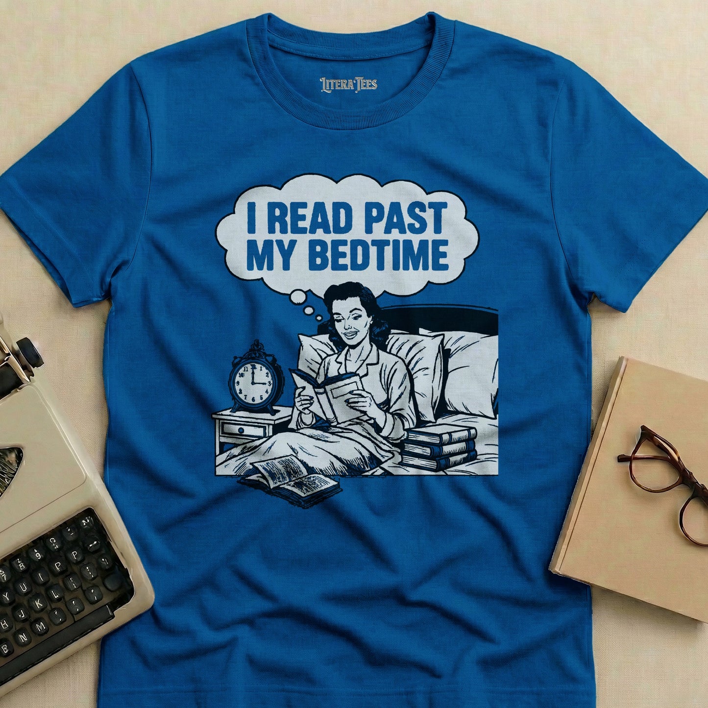 Blue t-shirt with cartoon of woman reading in bed, text "I read past my bedtime".