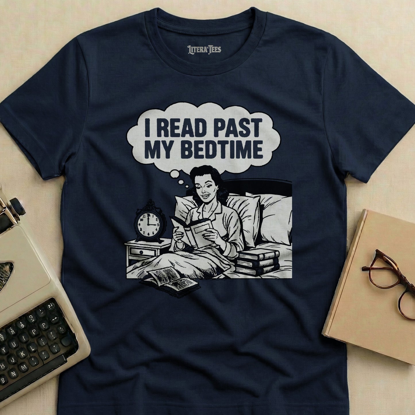 Dark blue t-shirt with white graphic of woman reading in bed, text "I READ PAST MY BEDTIME".