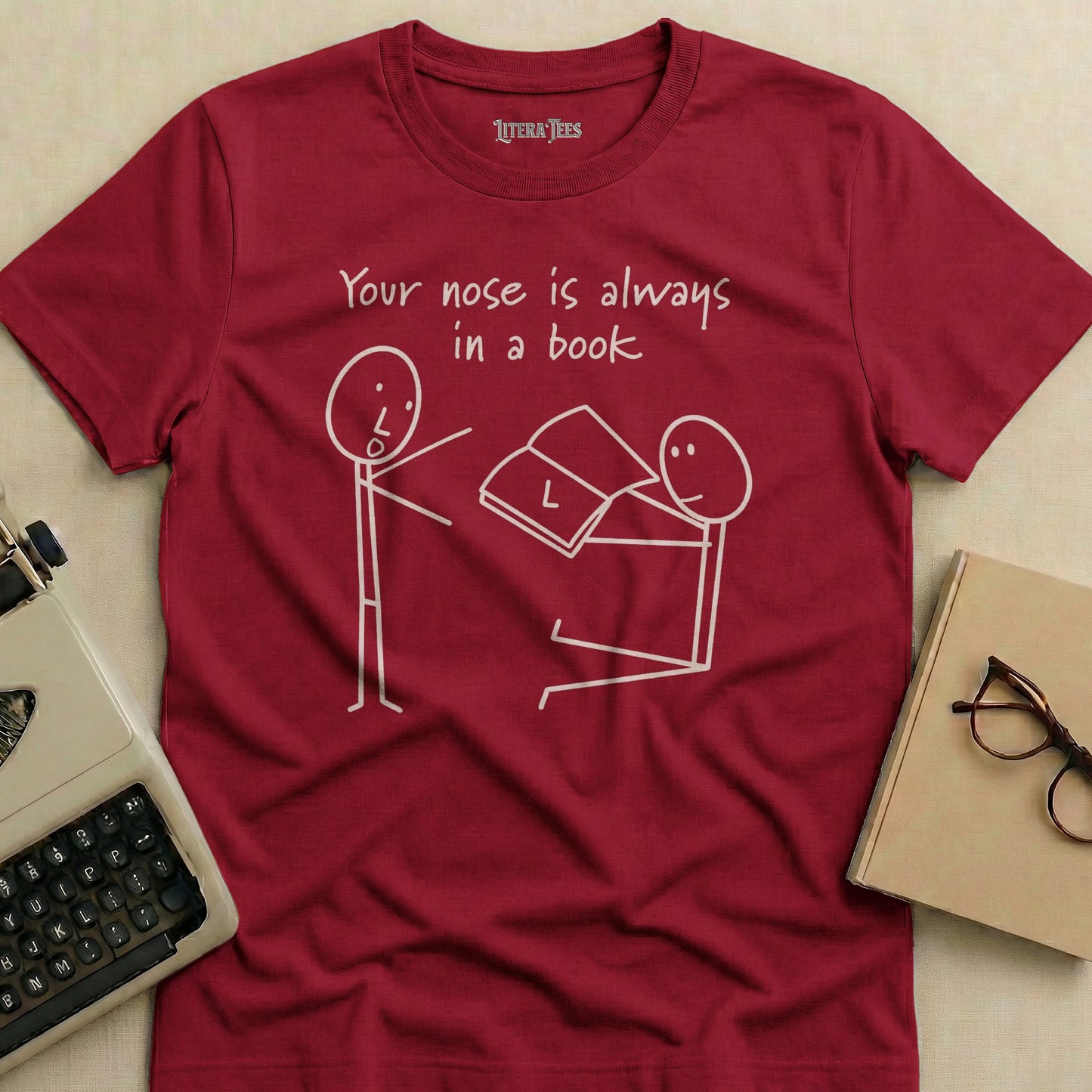 Maroon t-shirt with "Your nose is always in a book" text and stick figures reading.