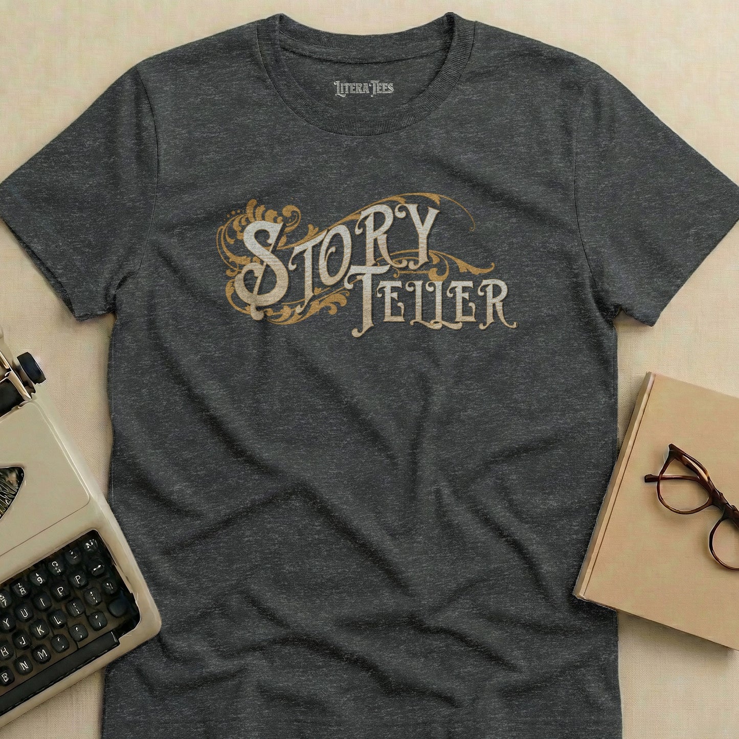 Dark grey t-shirt with "STORY TELLER" in ornate gold lettering.