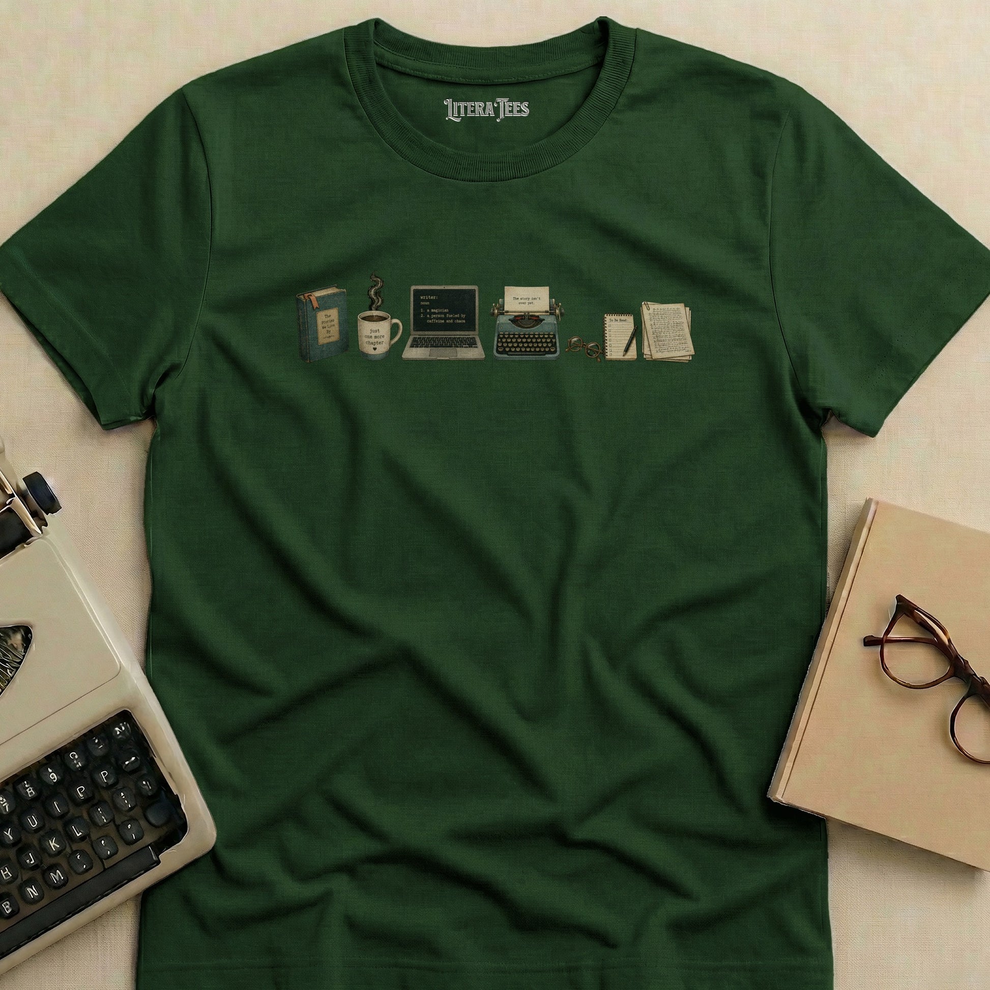 Green t-shirt with writer-themed graphic: book, coffee, laptop, typewriter, glasses, and notebooks.