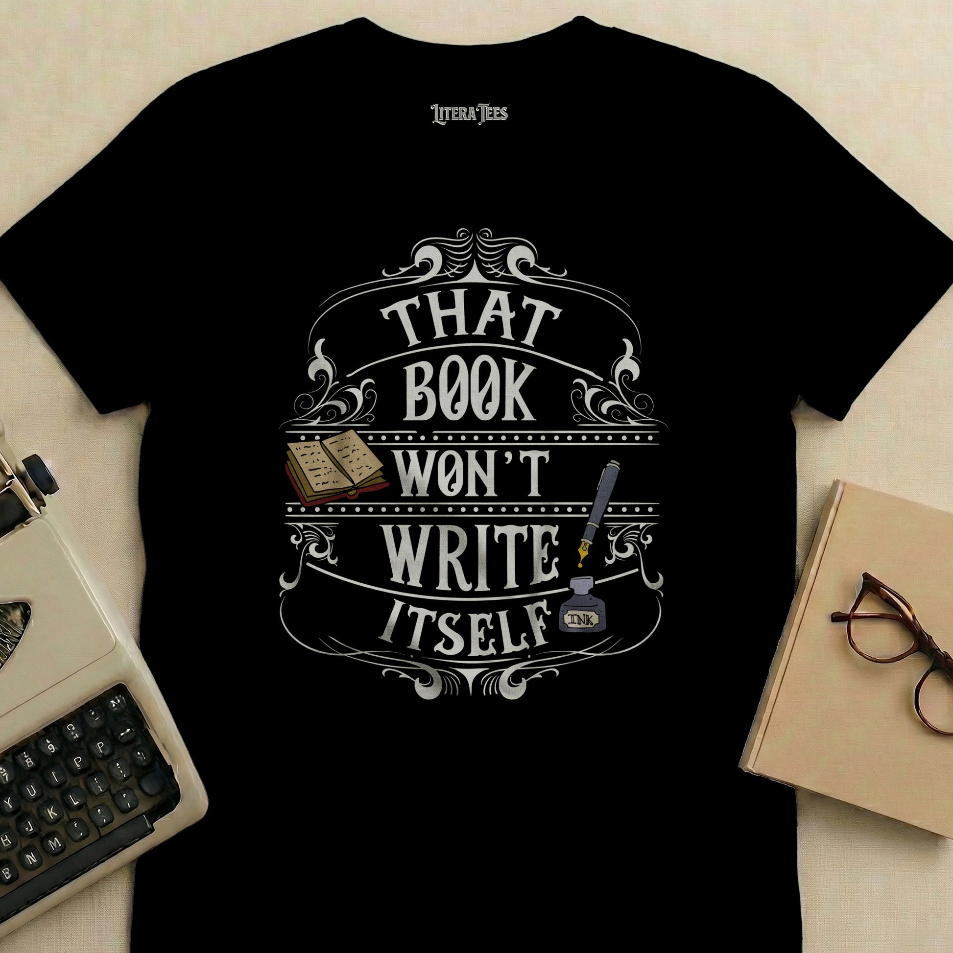 Black t-shirt with "That Book Won't Write Itself" text and inkwell graphic.