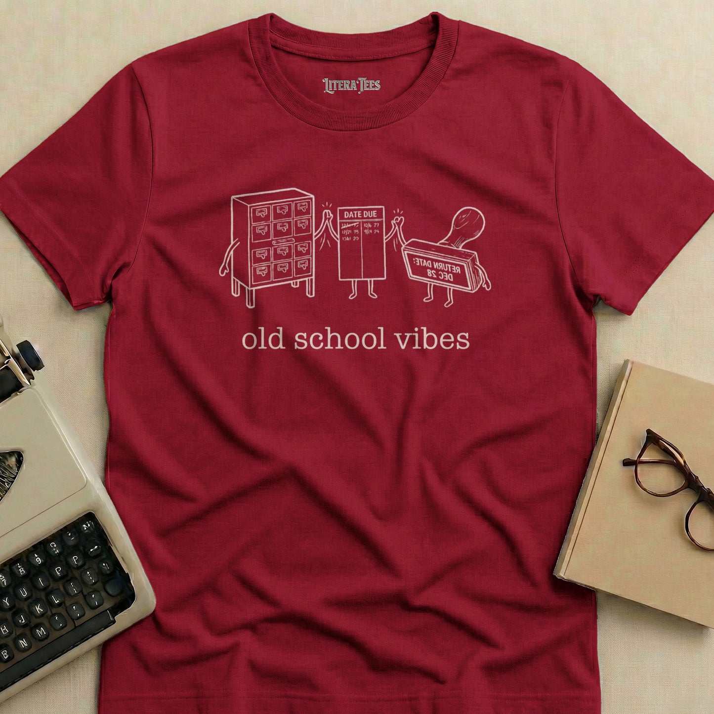 Burgundy t-shirt with "old school vibes" text and library catalog card and stamp graphics.