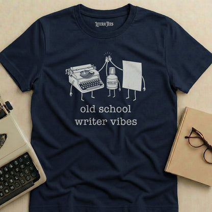 Navy t-shirt with cartoon typewriter and White-Out pen giving a high-five, saying "old school writer vibes".