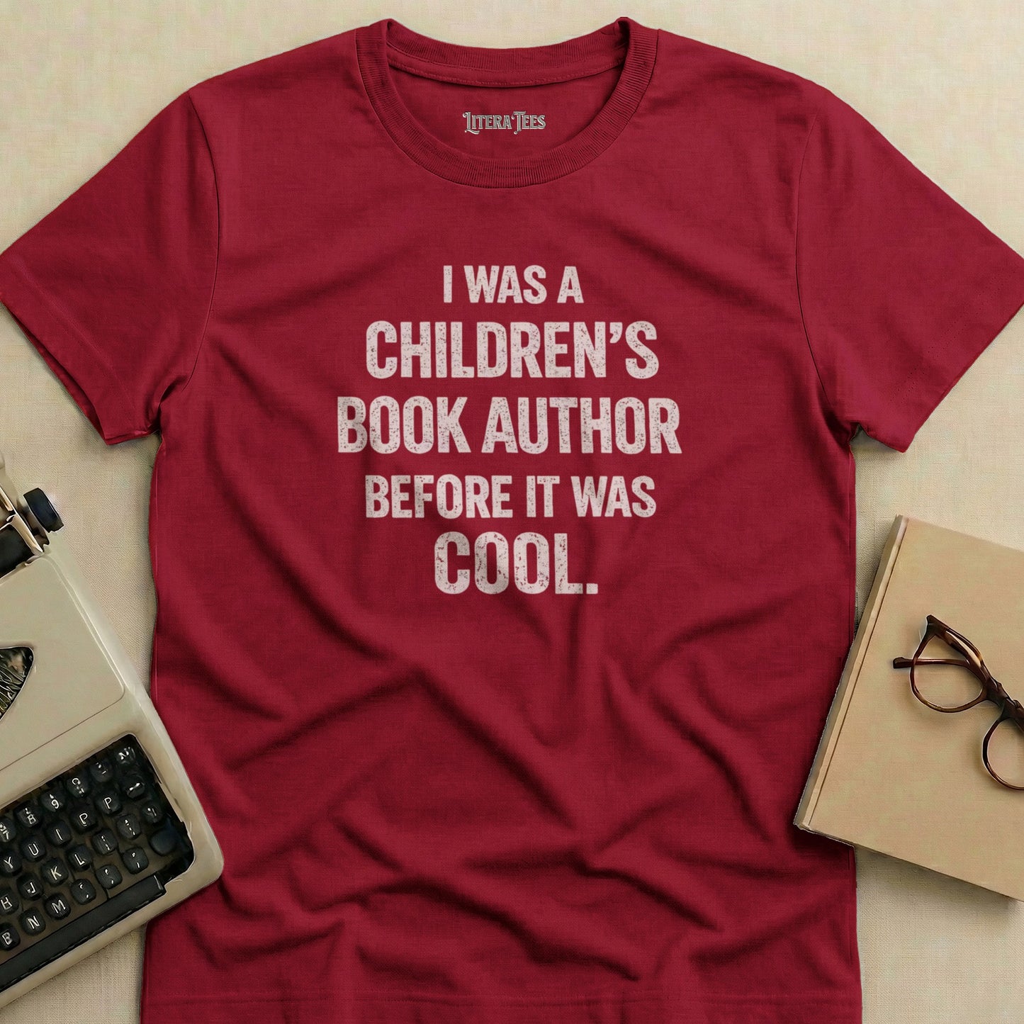 Crimson t-shirt with "I WAS A CHILDREN'S BOOK AUTHOR BEFORE IT WAS COOL" text.