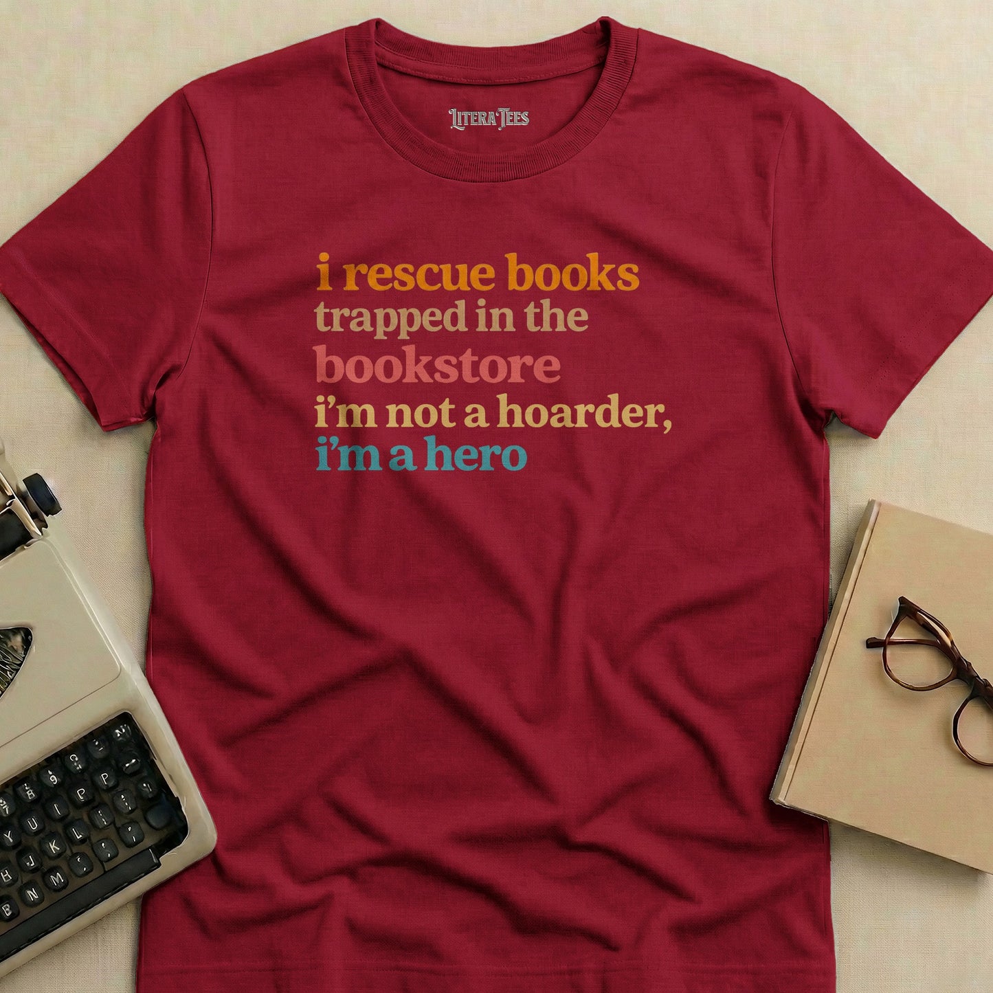 Maroon t-shirt with "i rescue books trapped in the bookstore i'm not a hoarder, i'm a hero" text.