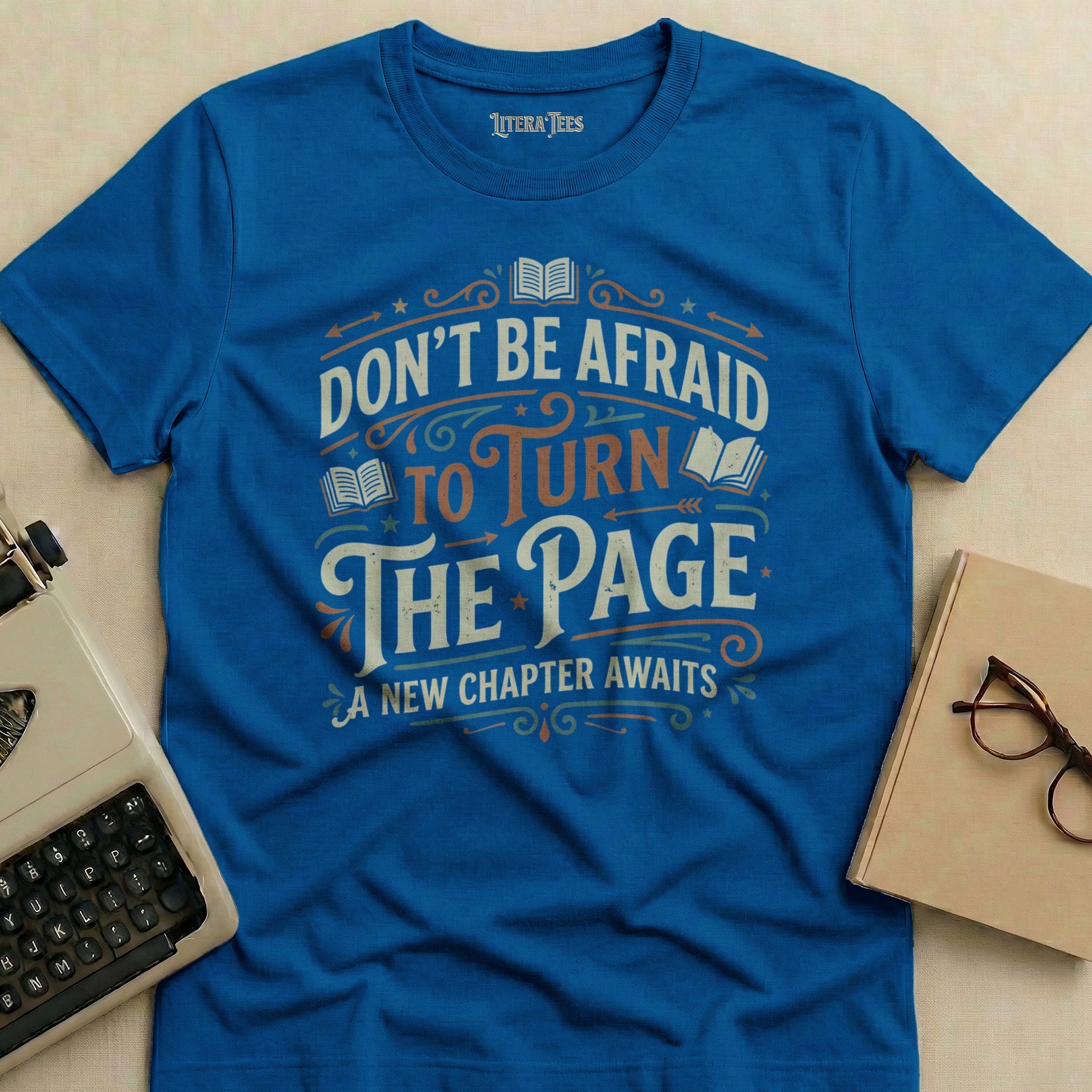 Blue t-shirt with "Don't Be Afraid To Turn The Page" text and books.