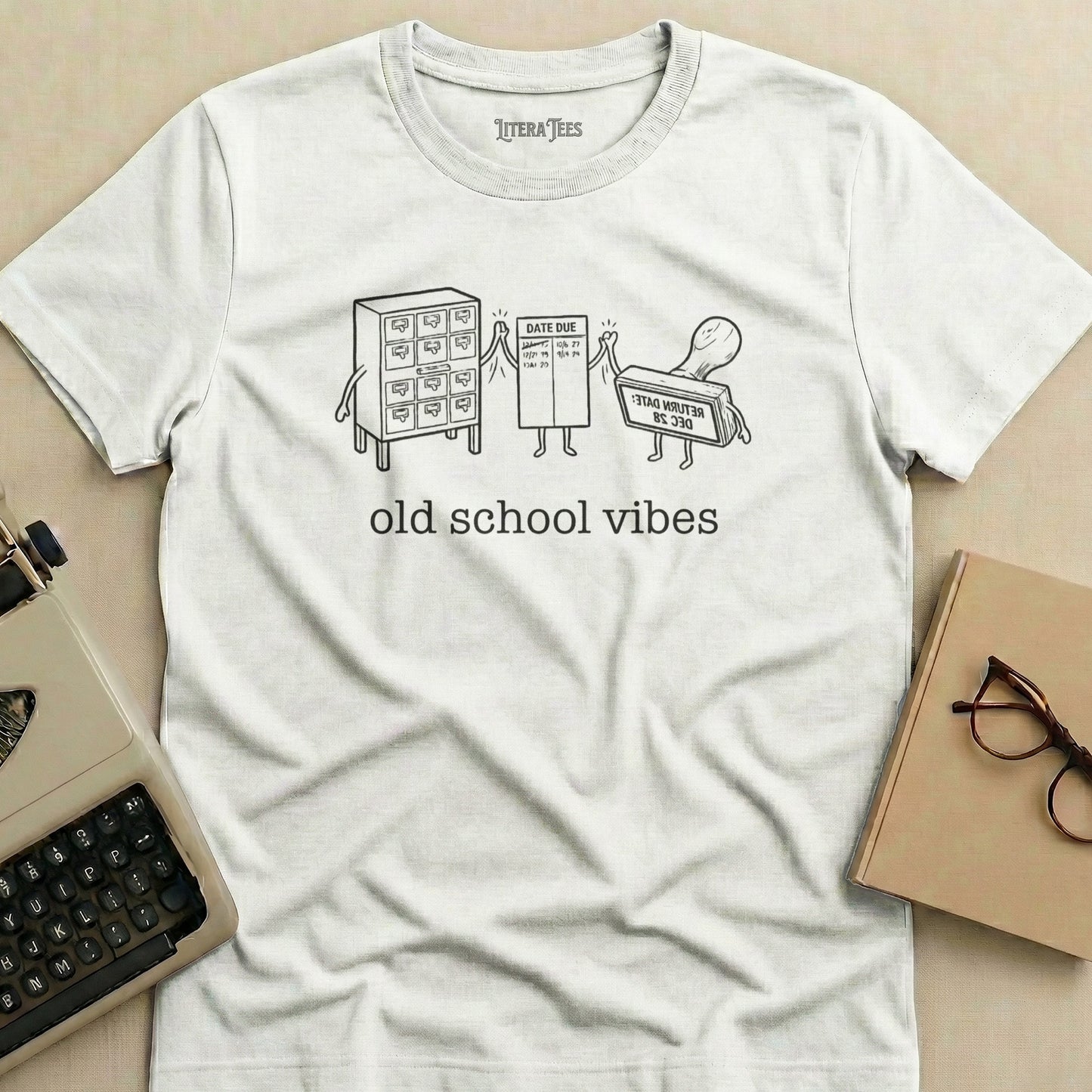 White t-shirt with cartoon library date due stamp, card catalog, and rubber stamp.