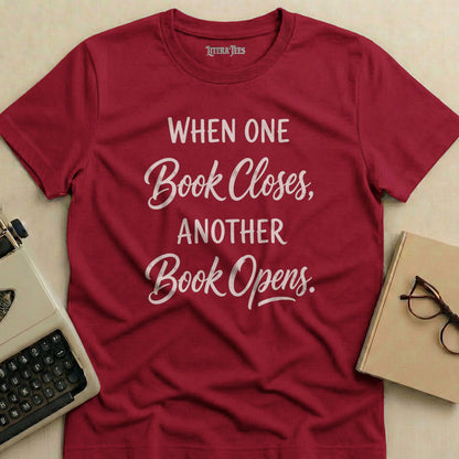 Maroon t-shirt with "When One Book Closes, Another Book Opens" text.