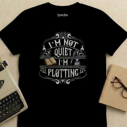 Black t-shirt with "I'm not quiet I'm plotting" text and inkwell graphic.