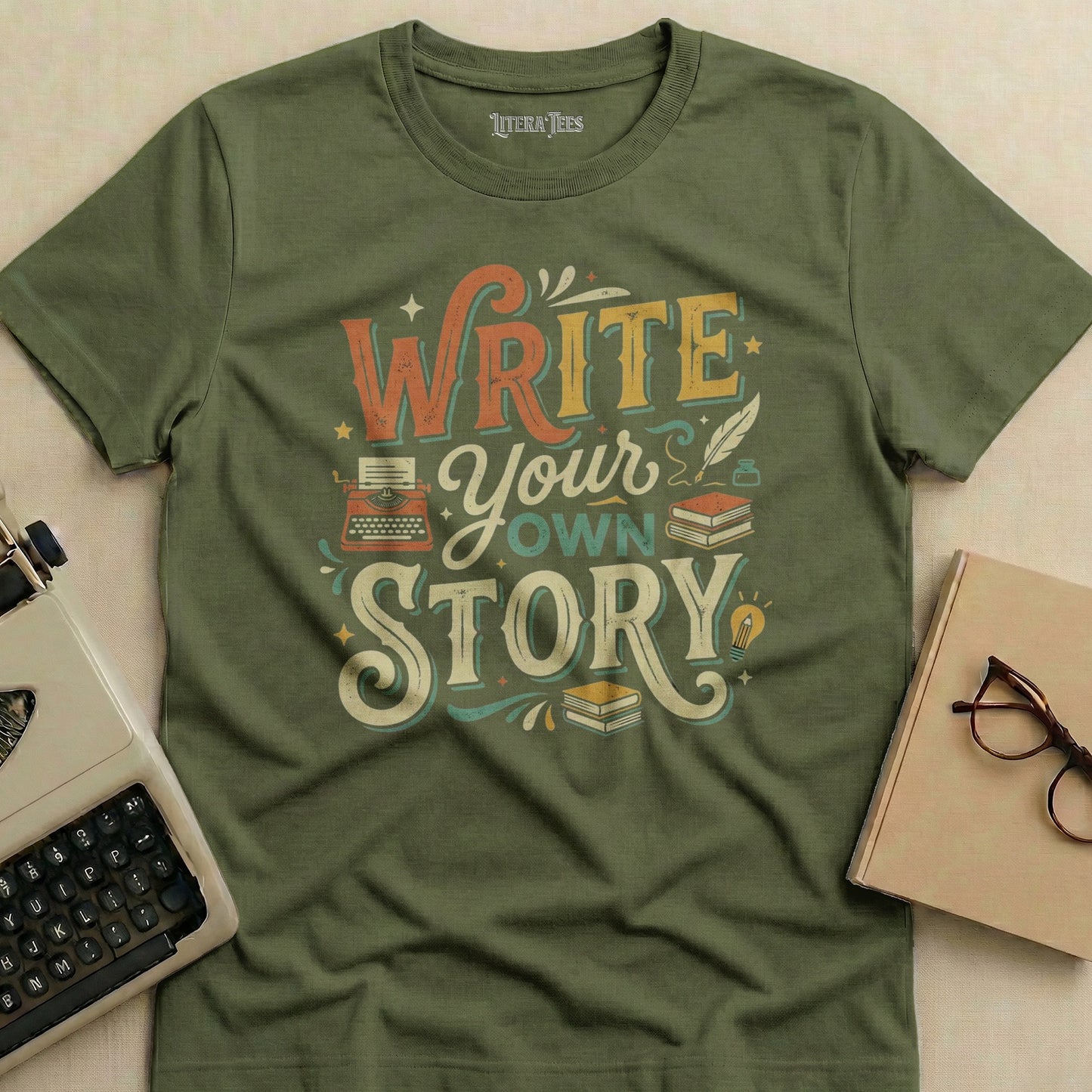 Olive t-shirt with "Write Your Own Story" text, typewriter, and books design.