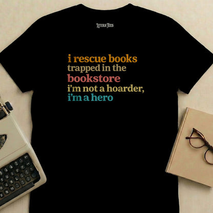 Black t-shirt with "i rescue books trapped in the bookstore i'm not a hoarder, i'm a hero" text.