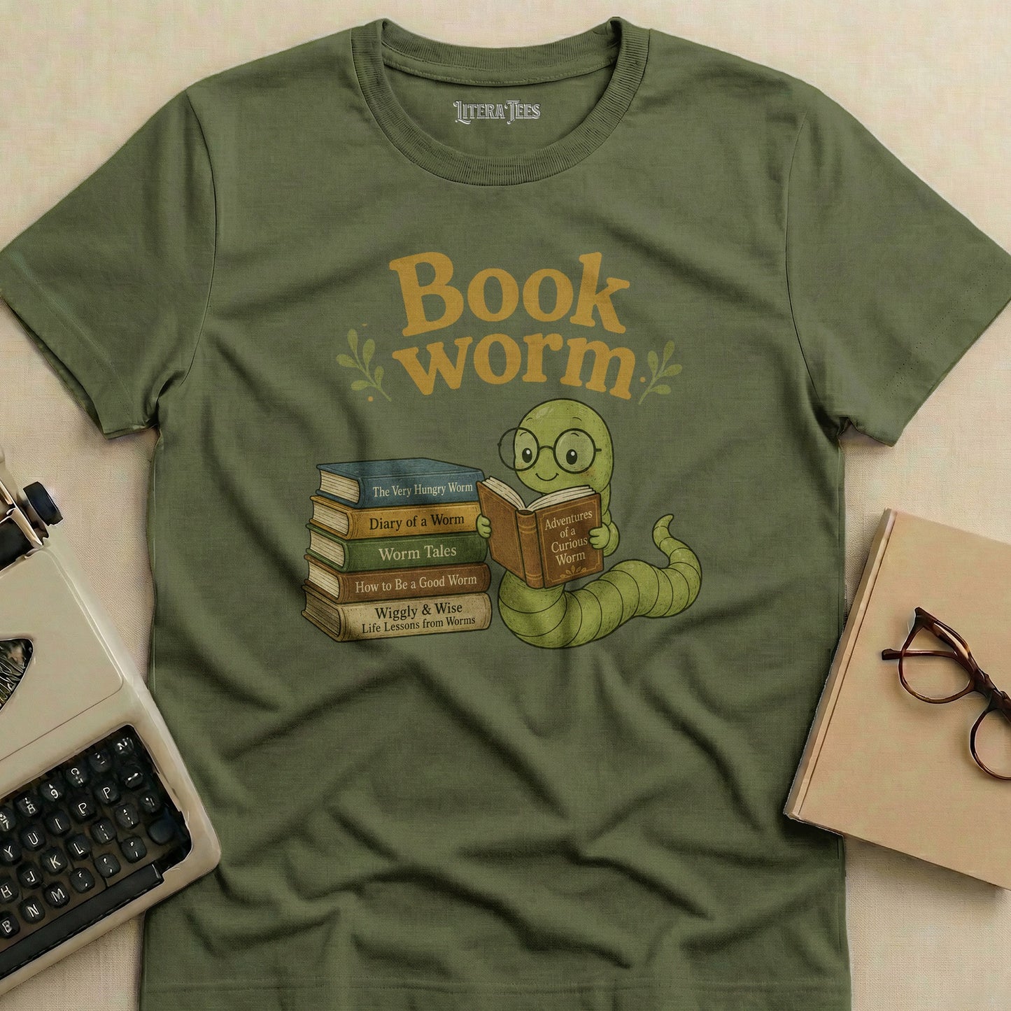Green t-shirt with a cartoon worm reading a book next to a stack of books.