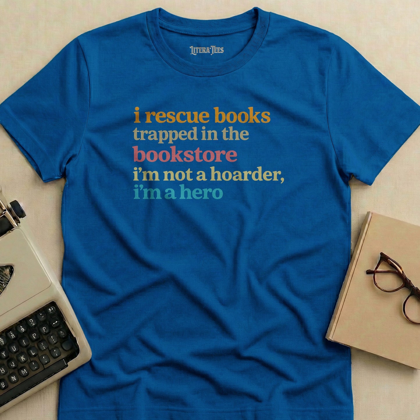 Blue t-shirt with text "i rescue books trapped in the bookstore i'm not a hoarder, i'm a hero".