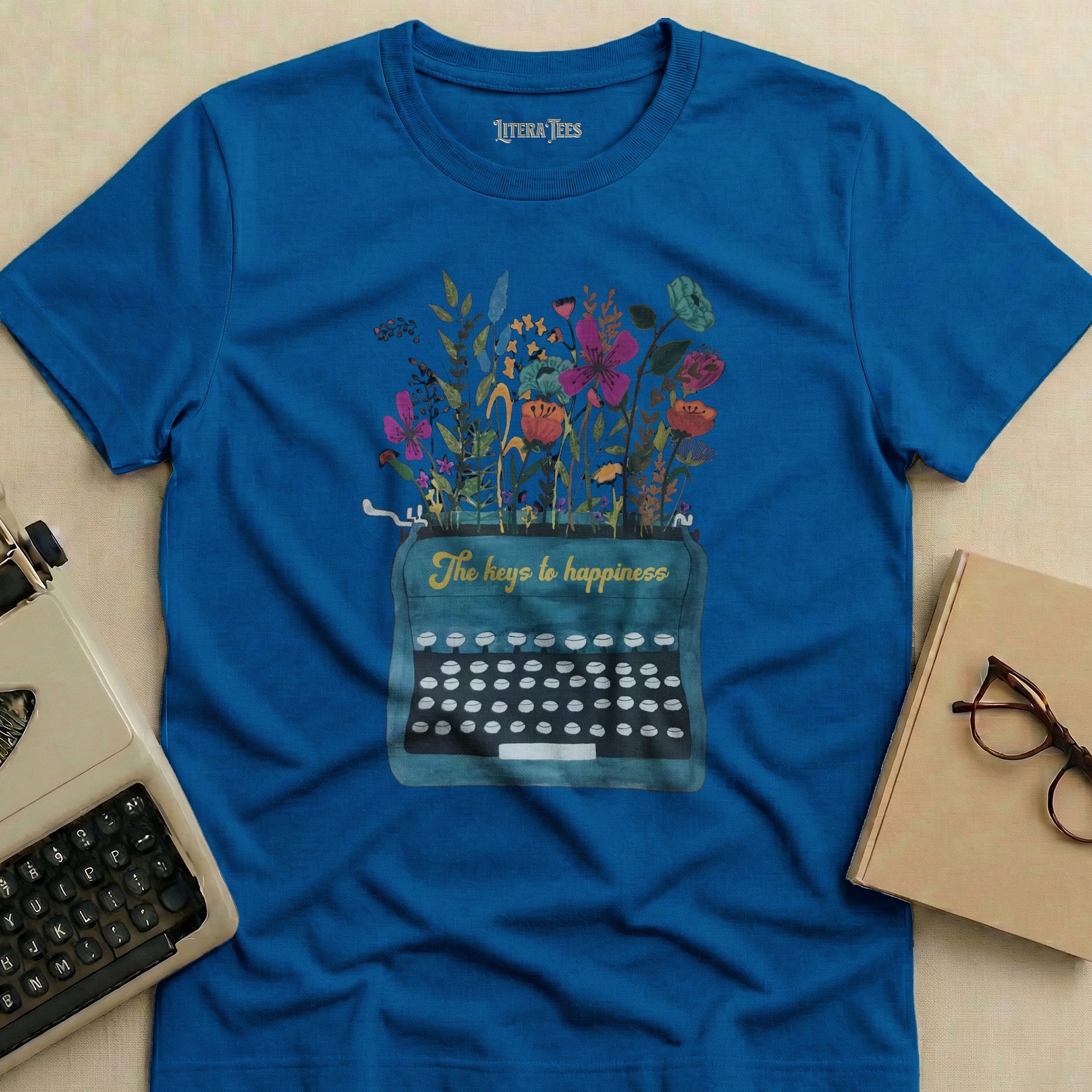 Blue t-shirt with vintage typewriter and flowers, reading "The keys to happiness."