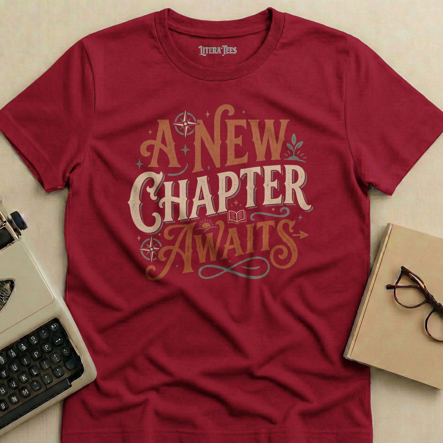 Maroon t-shirt with "A New Chapter Awaits" text in ornate lettering.