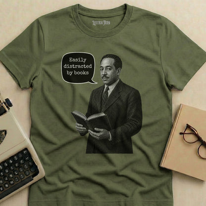 Olive green t-shirt with illustration of man reading, saying "Easily distracted by books."
