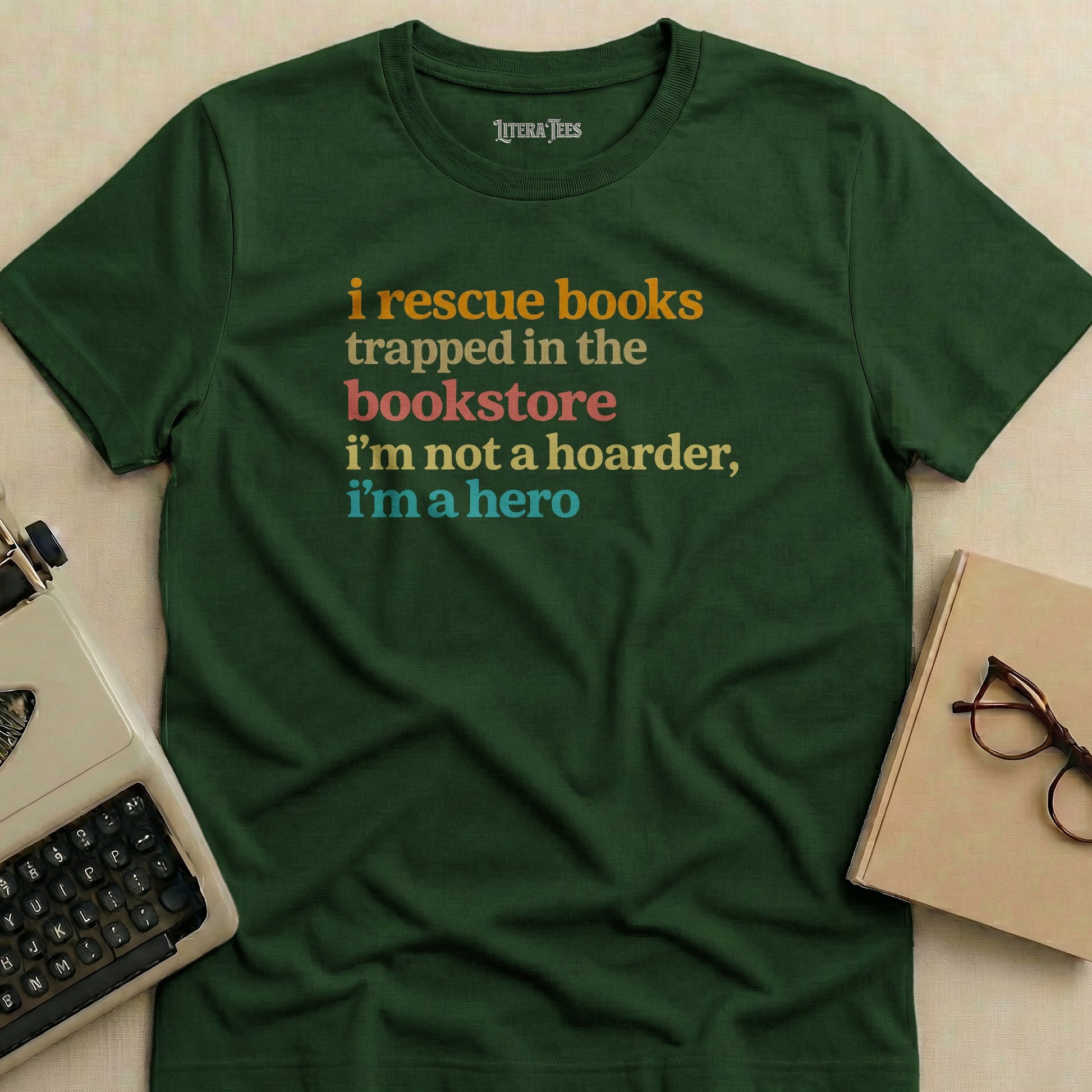 Green t-shirt with "i rescue books trapped in the bookstore i'm not a hoarder, i'm a hero" text.
