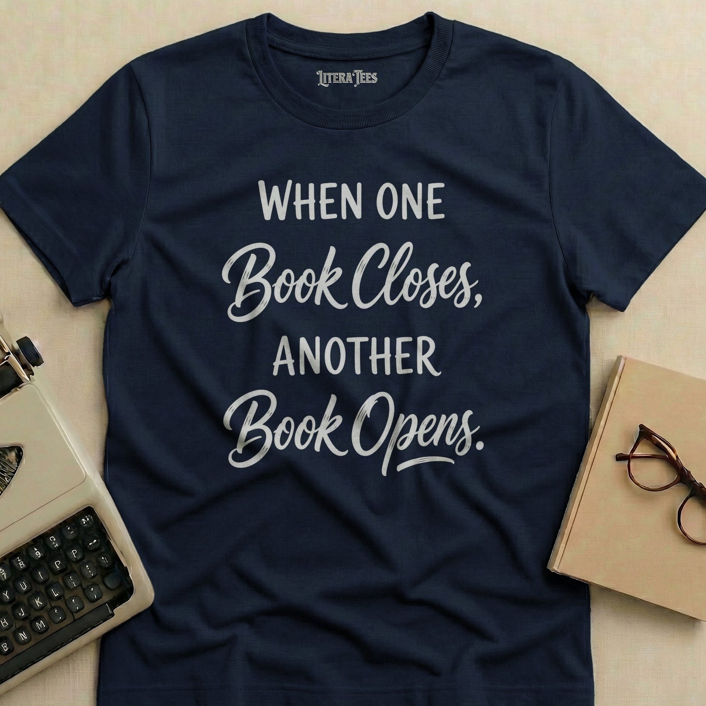 Navy t-shirt with text "When One Book Closes, Another Book Opens."