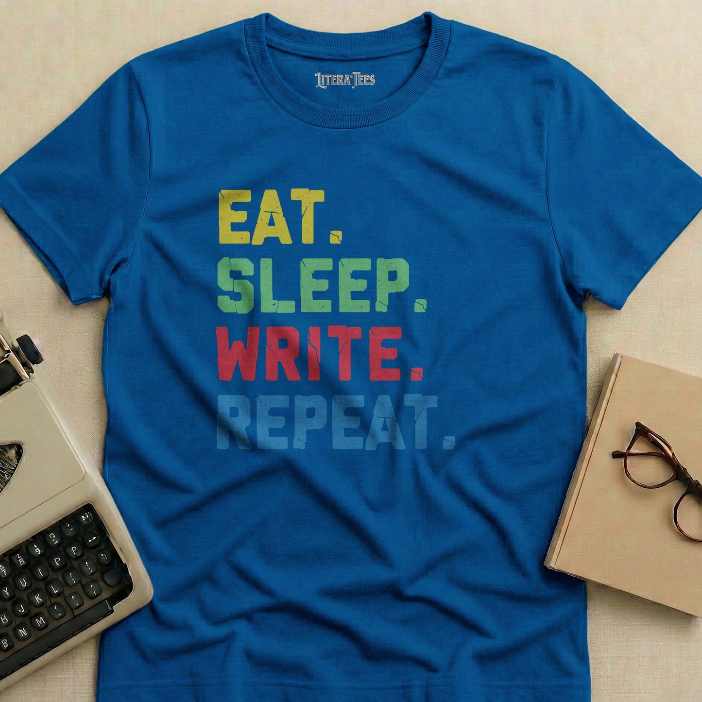 Blue t-shirt with "EAT. SLEEP. WRITE. REPEAT." text in colorful block letters.