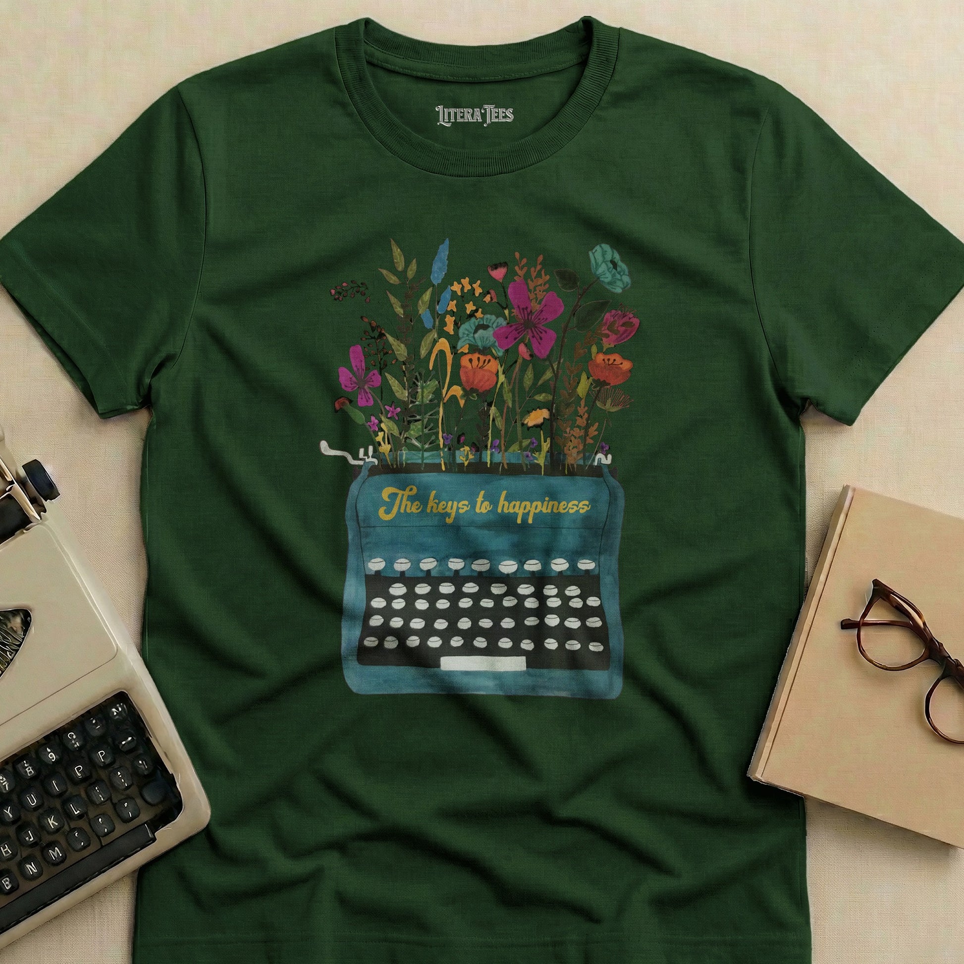 Dark green t-shirt with "The keys to happiness" typewriter and floral design.