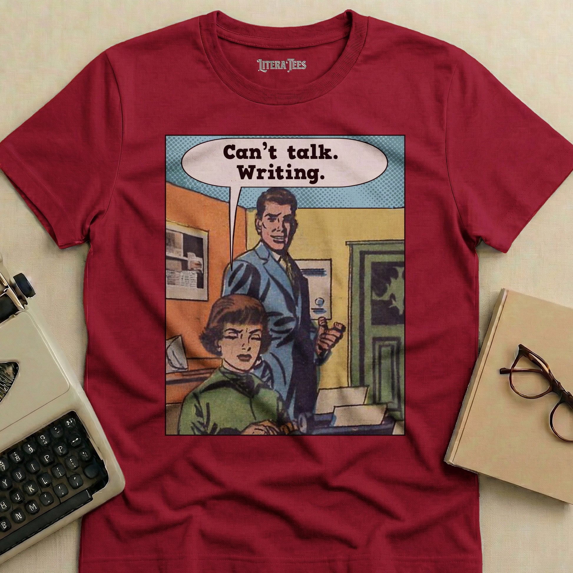 Maroon t-shirt with comic panel: "Can't talk. Writing."
