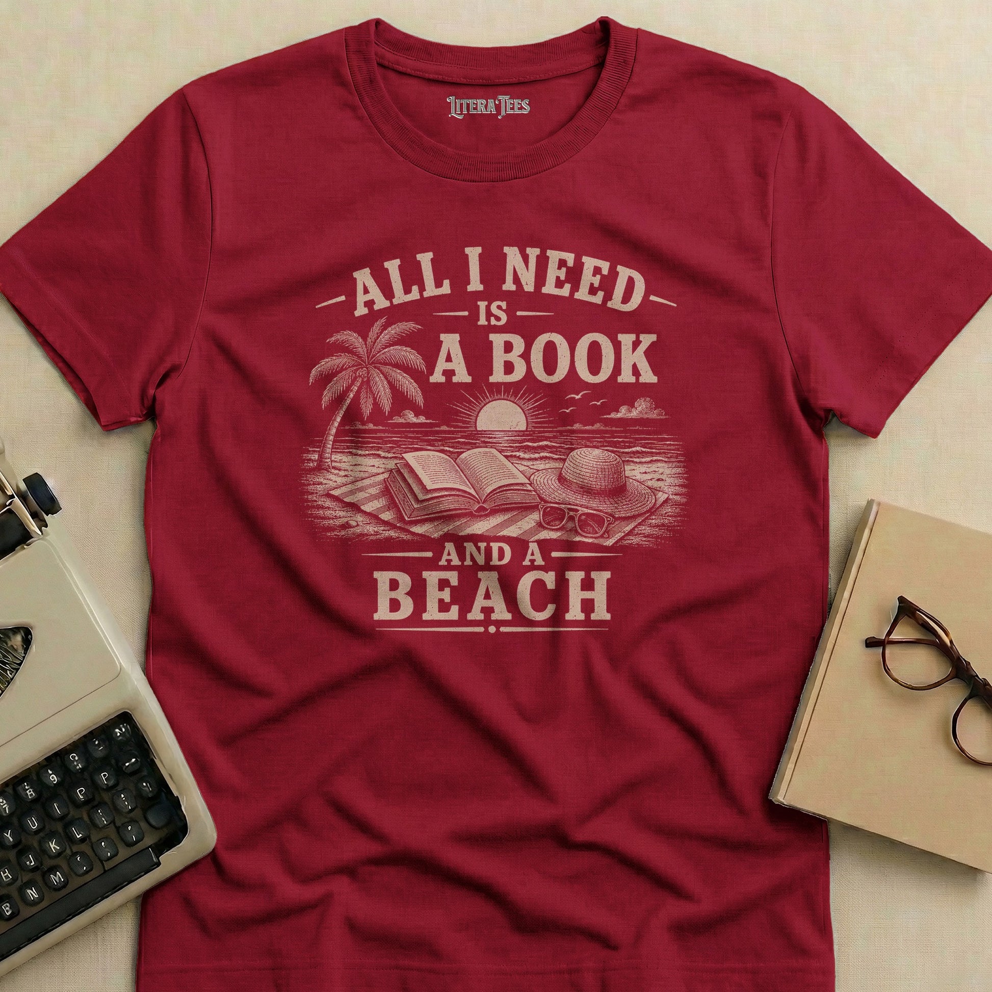 Burgundy t-shirt with "All I Need Is A Book And A Beach" text and beach graphic.