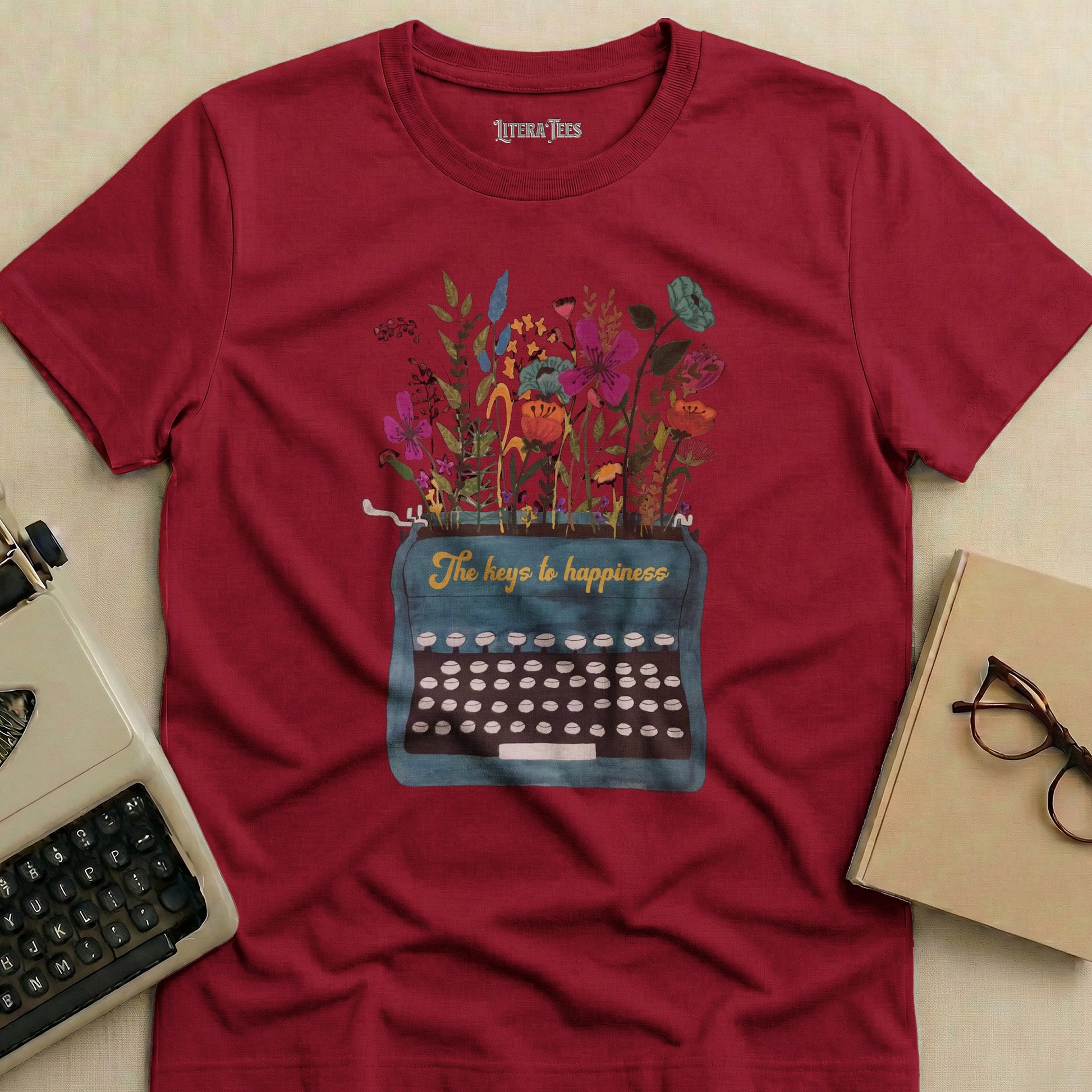 Burgundy t-shirt with vintage typewriter and floral design, "The keys to happiness".