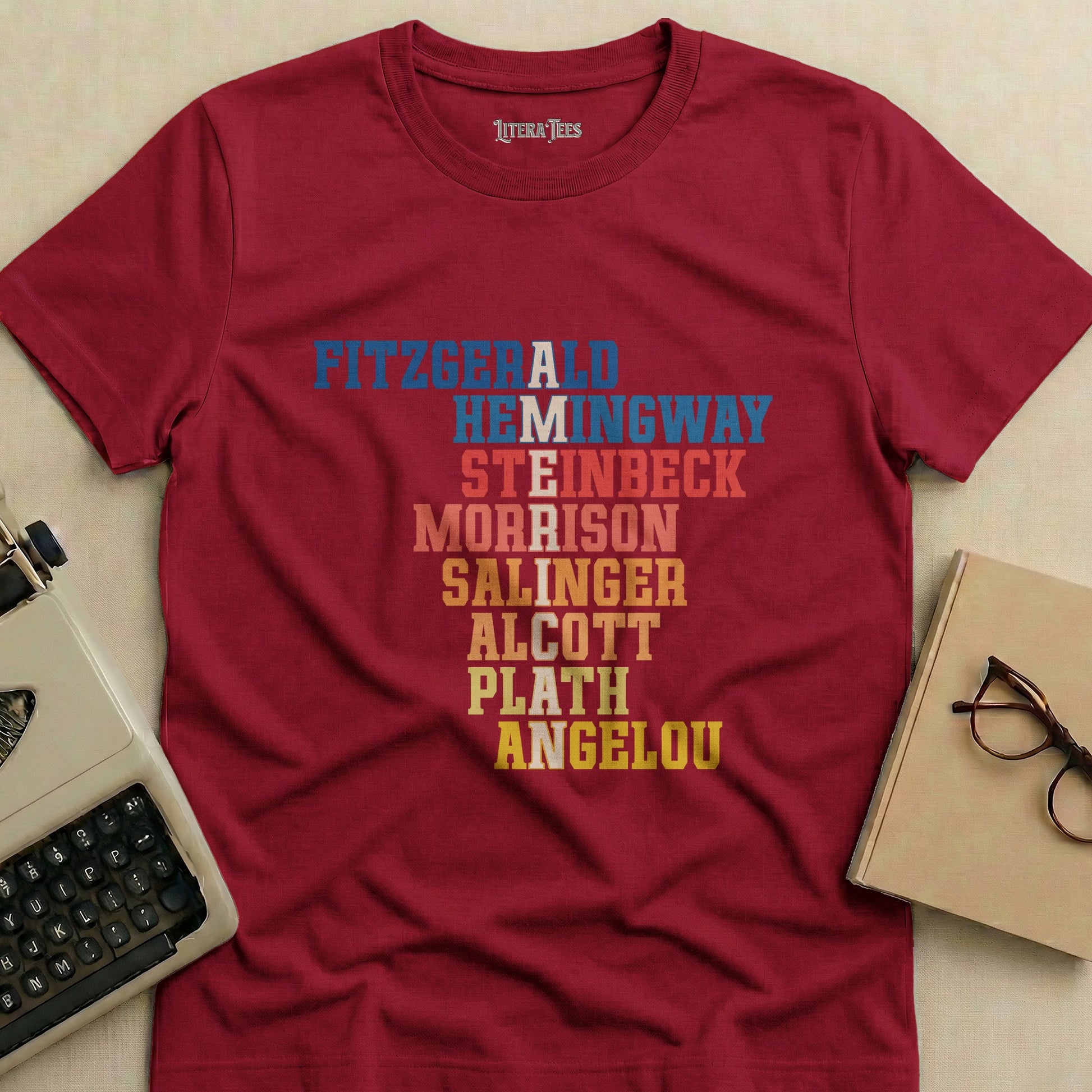 Maroon t-shirt with author names: Fitzgerald, Hemingway, Steinbeck, Morrison, Salinger, Alcott, Plath, Angelou.
