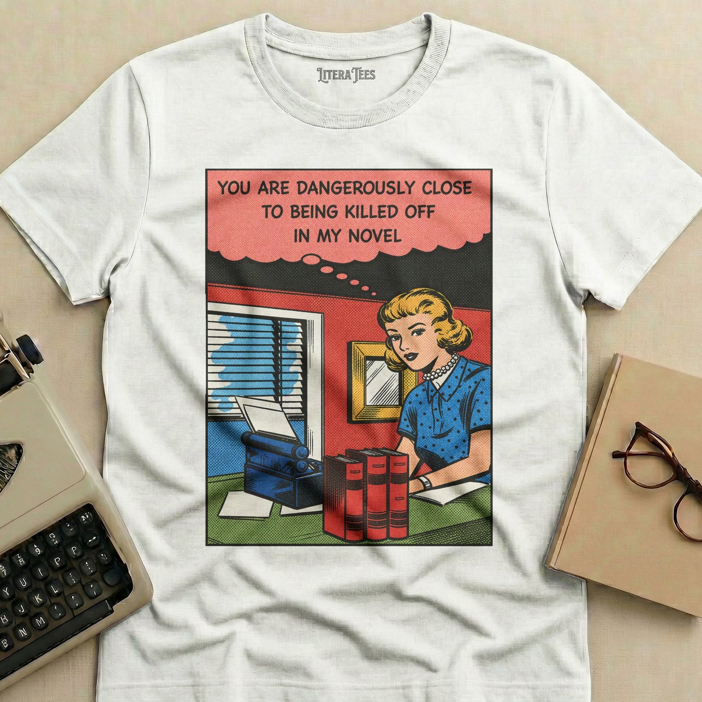 T-shirt with comic-style illustration and text: "You are dangerously close to being killed off in my novel."