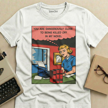 T-shirt with comic-style illustration and text: "You are dangerously close to being killed off in my novel."