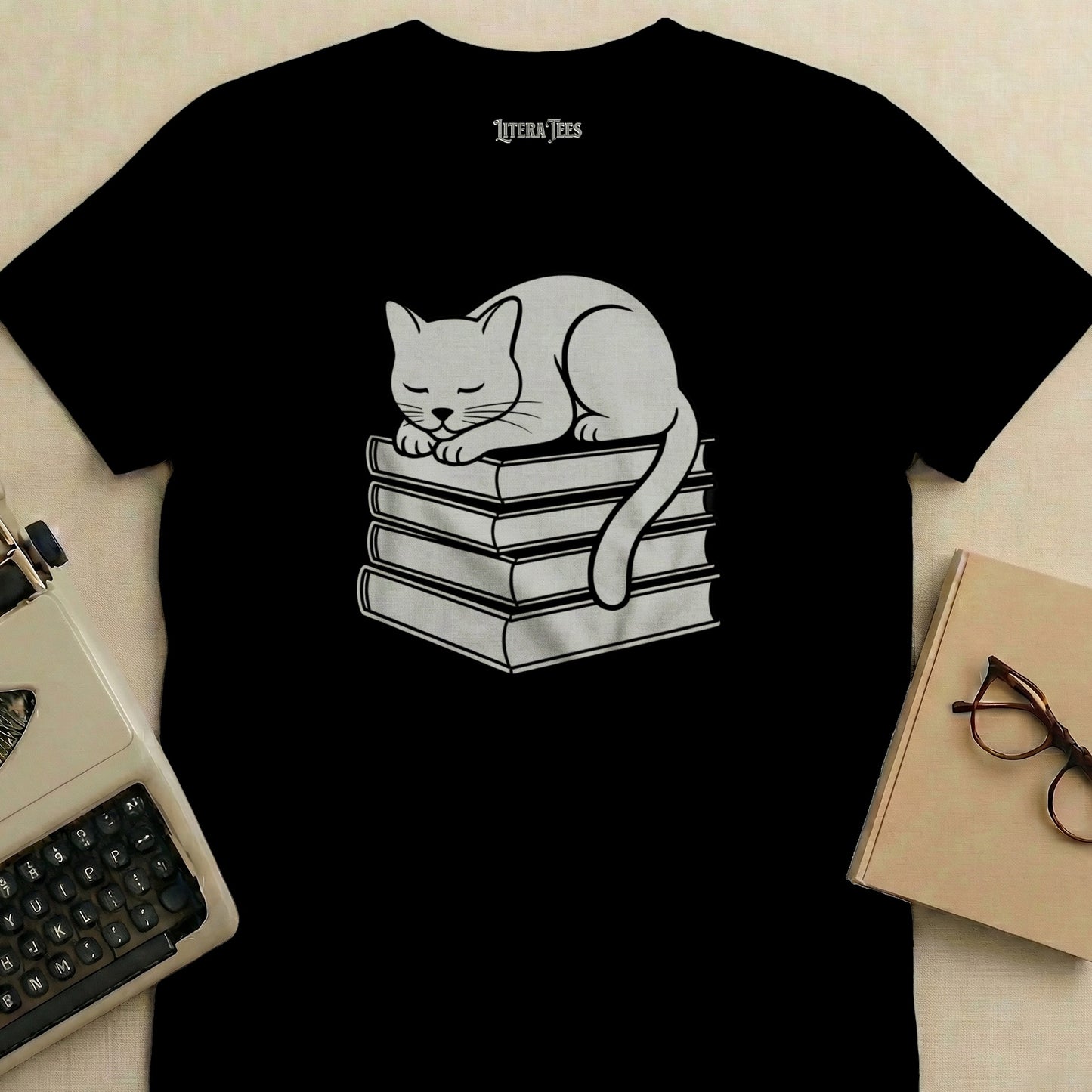 Black t-shirt with white cat sleeping on stack of books graphic.