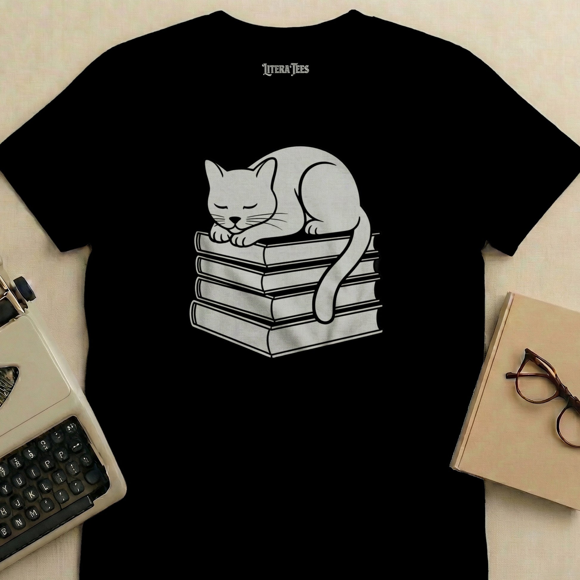 Black t-shirt with white cat sleeping on stack of books graphic.