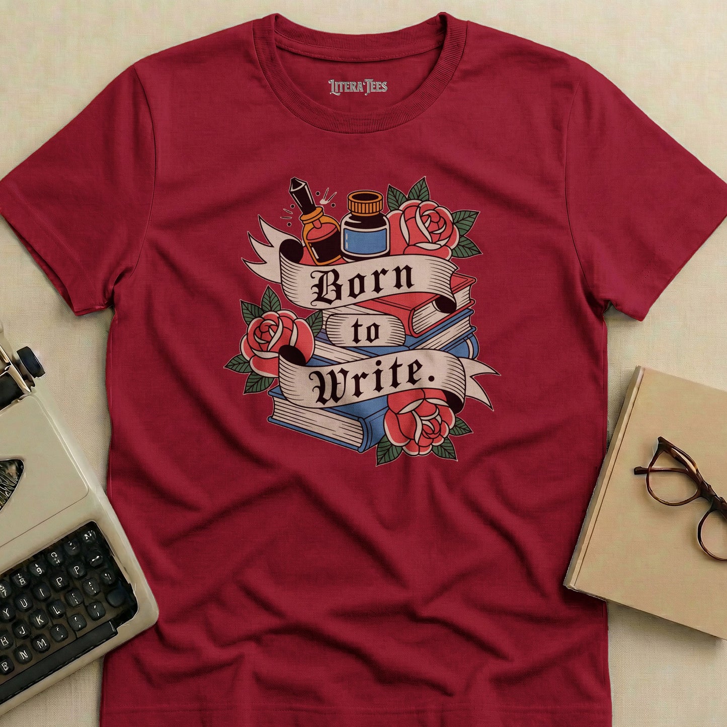 Maroon t-shirt with "Born to Write." text, books, roses, and inkwell design.