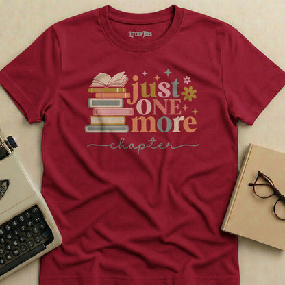 Burgundy t-shirt with "Just One More Chapter" and stacked books graphic.