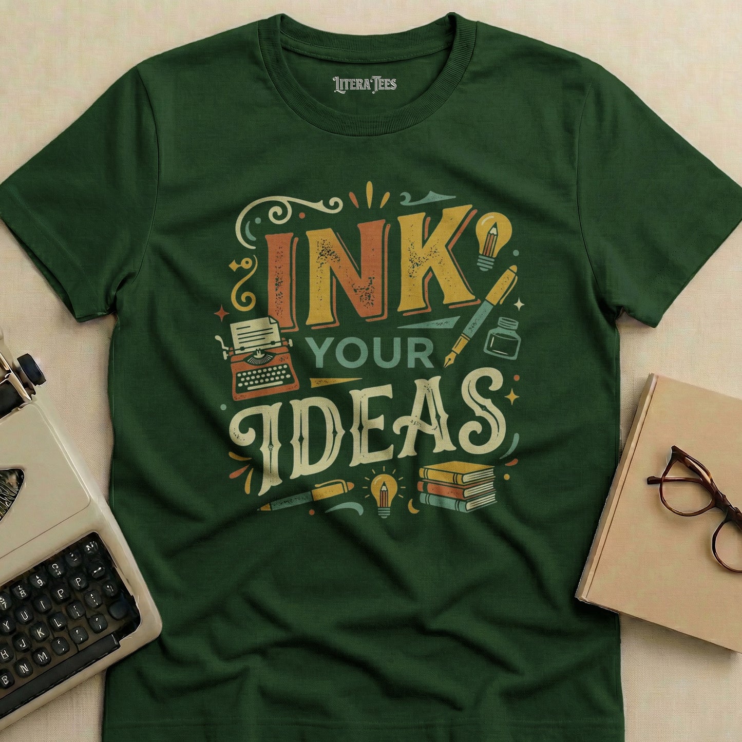 Green t-shirt with "INK YOUR IDEAS" text, typewriter, books, and pens.
