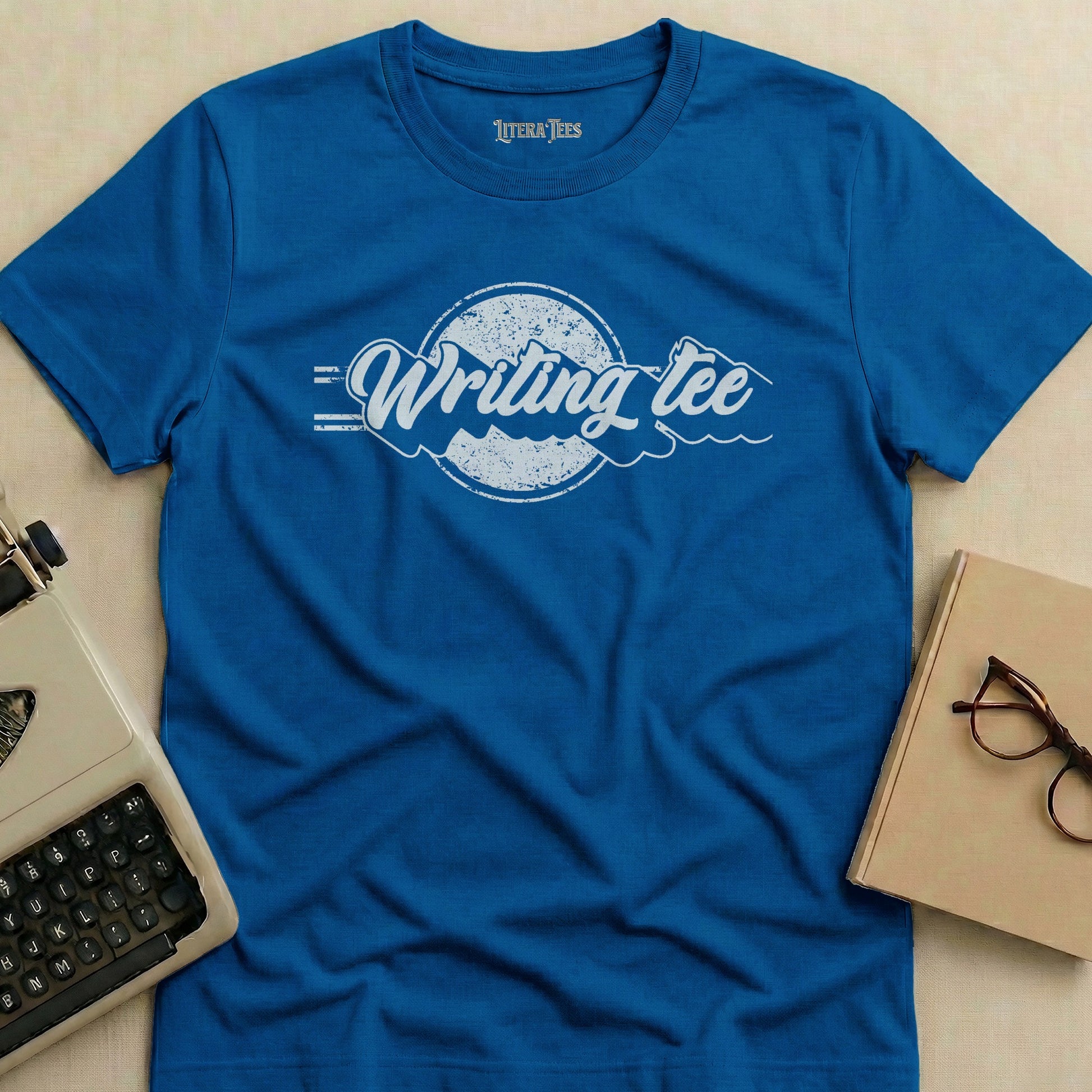 Blue t-shirt with "Writing tee" logo and typewriter graphic.
