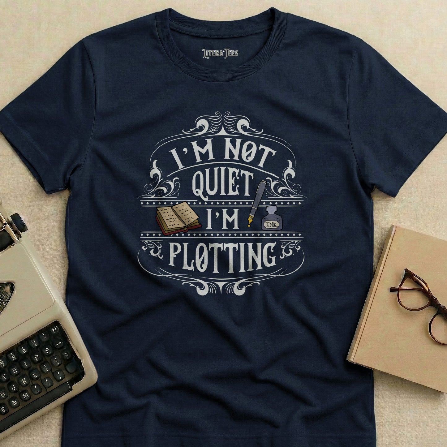 Navy t-shirt with "I'm Not Quiet I'm Plotting" text and inkwell illustration.