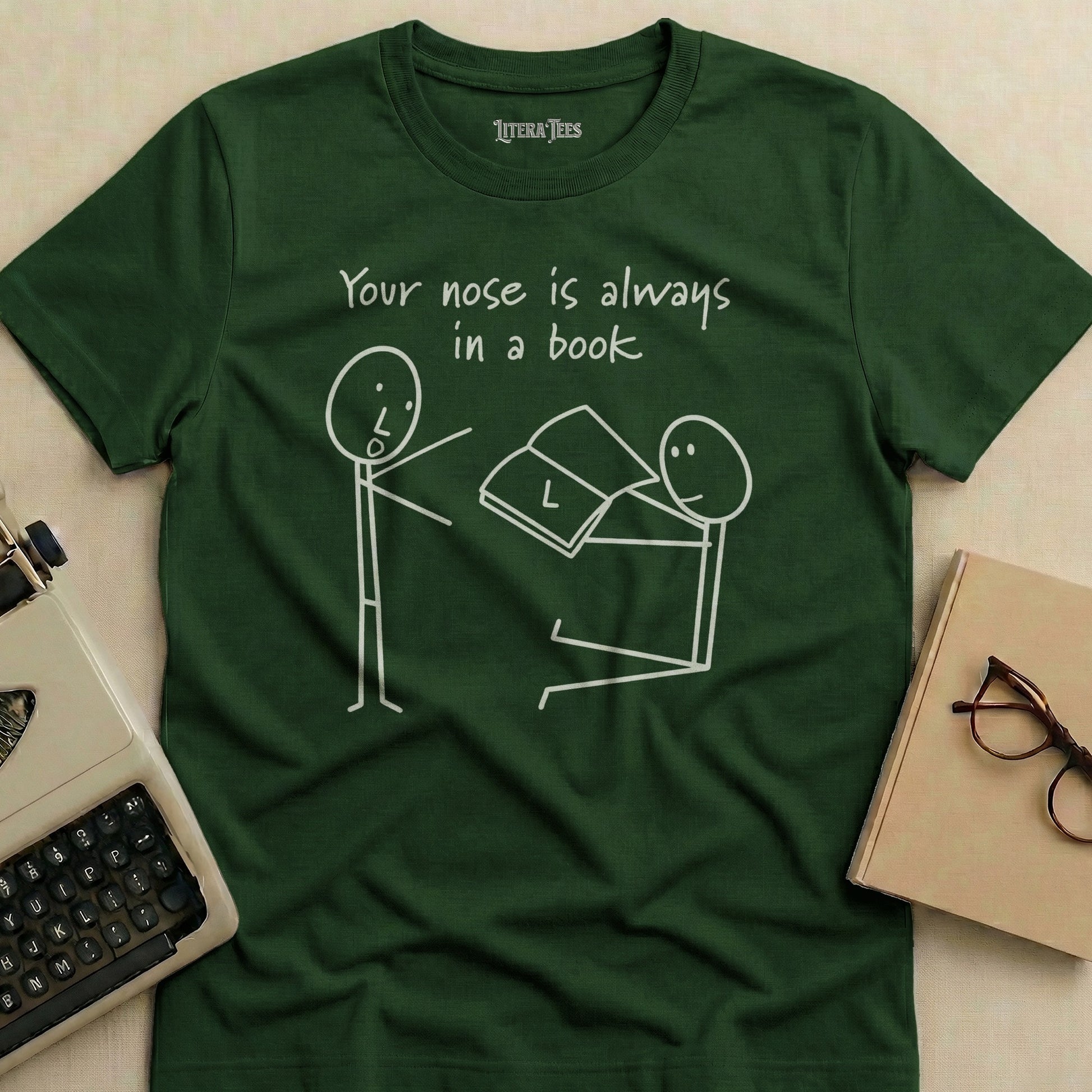 Dark green t-shirt with stick figures reading, "Your nose is always in a book."
