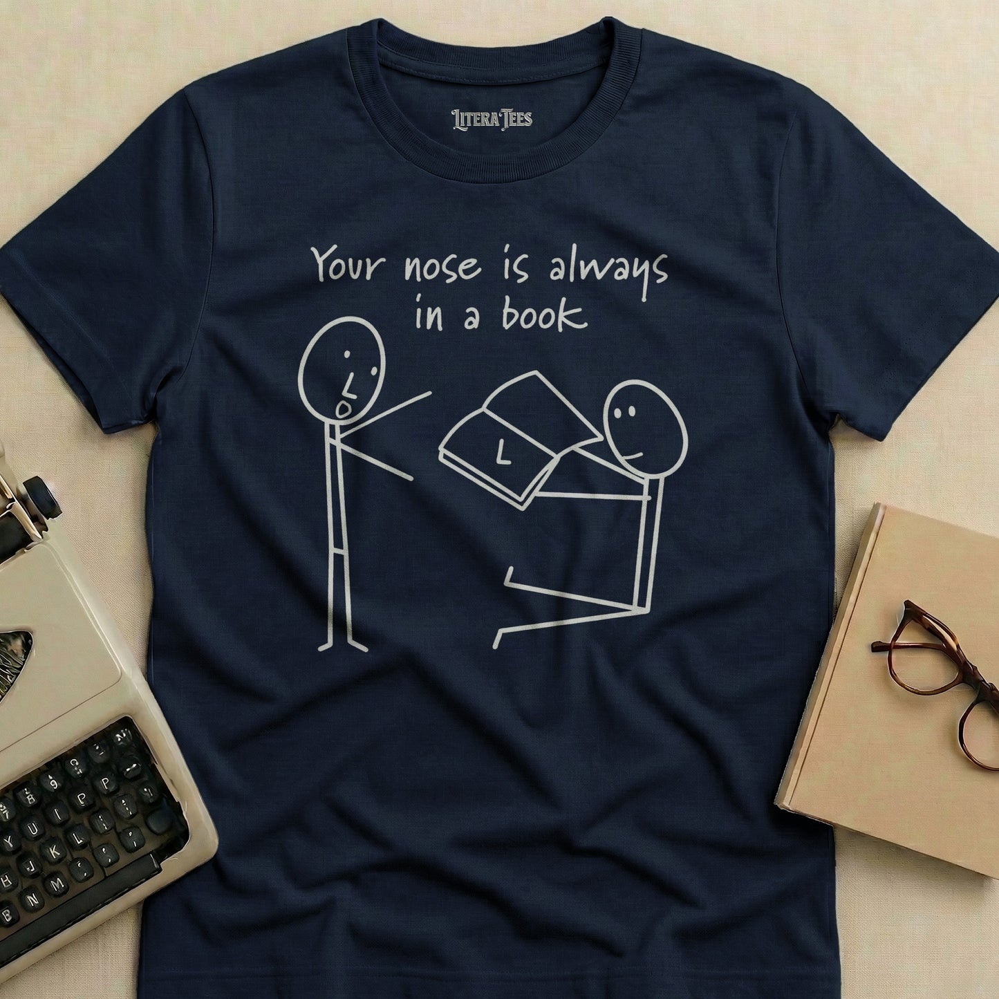 Navy t-shirt with white line drawing of two figures and text "Your nose is always in a book."