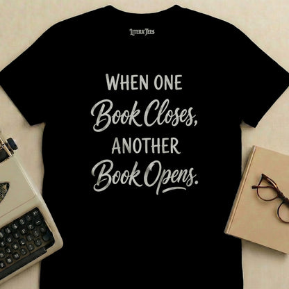 Black t-shirt with "When One Book Closes, Another Book Opens" text.