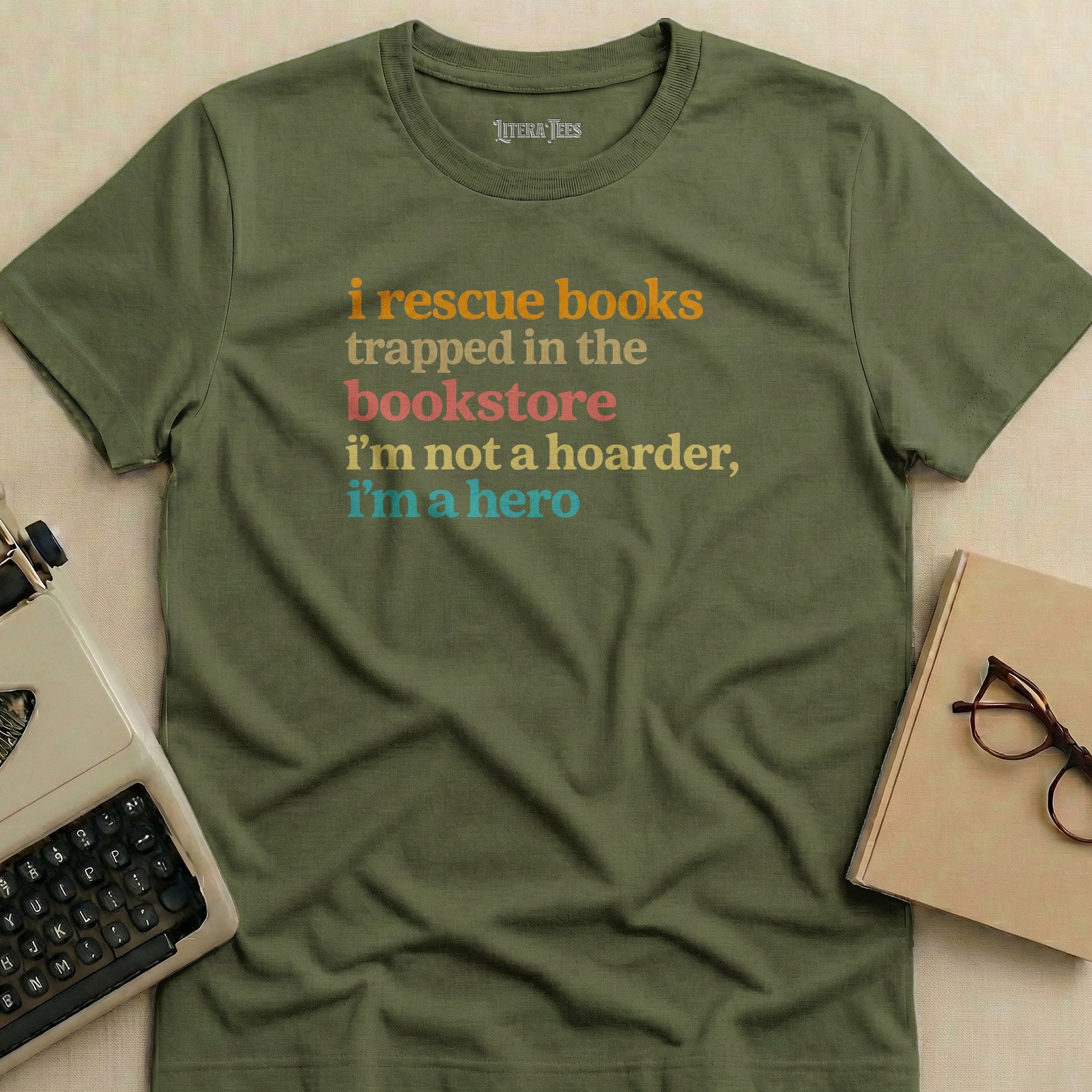 Olive green t-shirt with text "i rescue books trapped in the bookstore i'm not a hoarder, i'm a hero".
