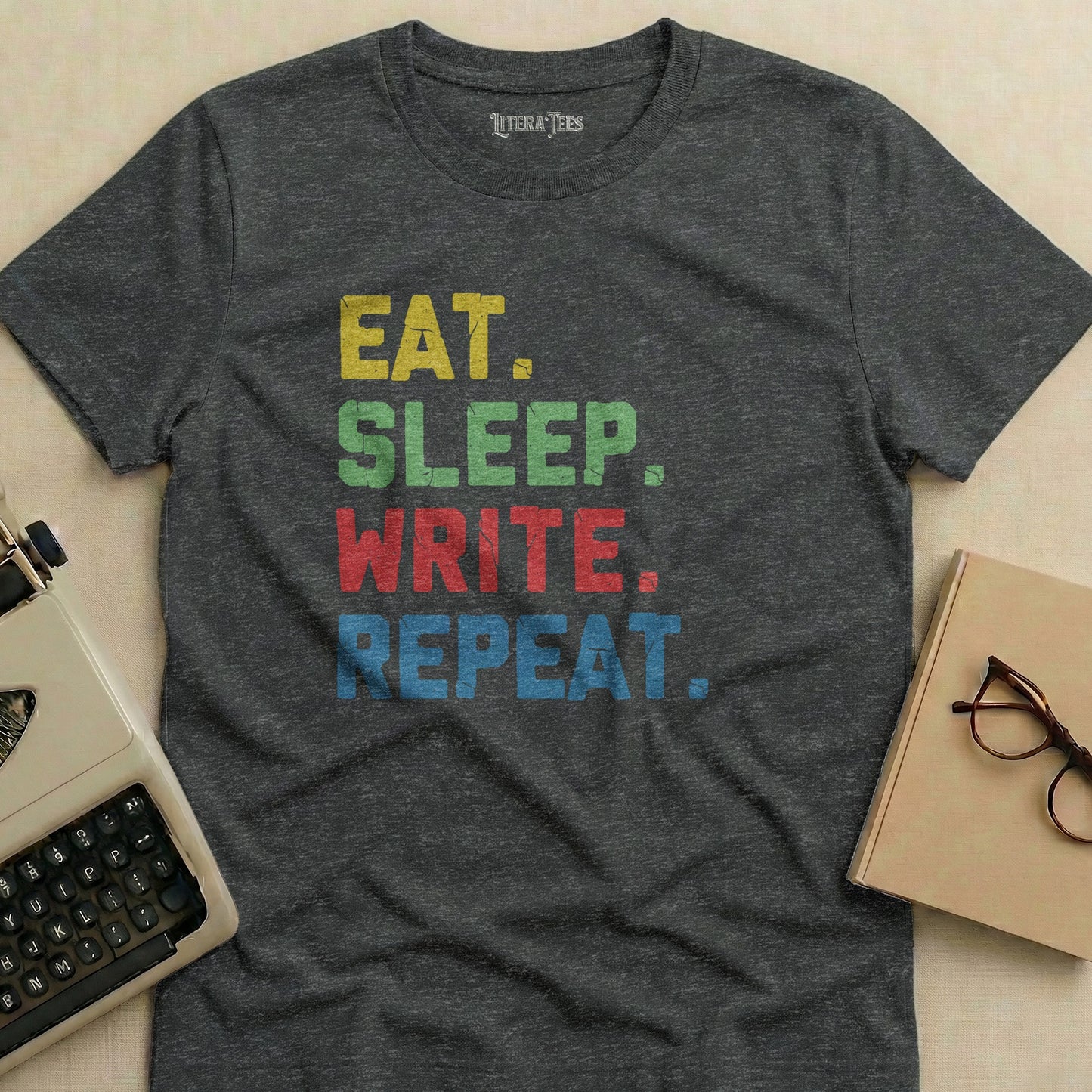 Dark gray t-shirt with "EAT. SLEEP. WRITE. REPEAT." in colorful block letters.