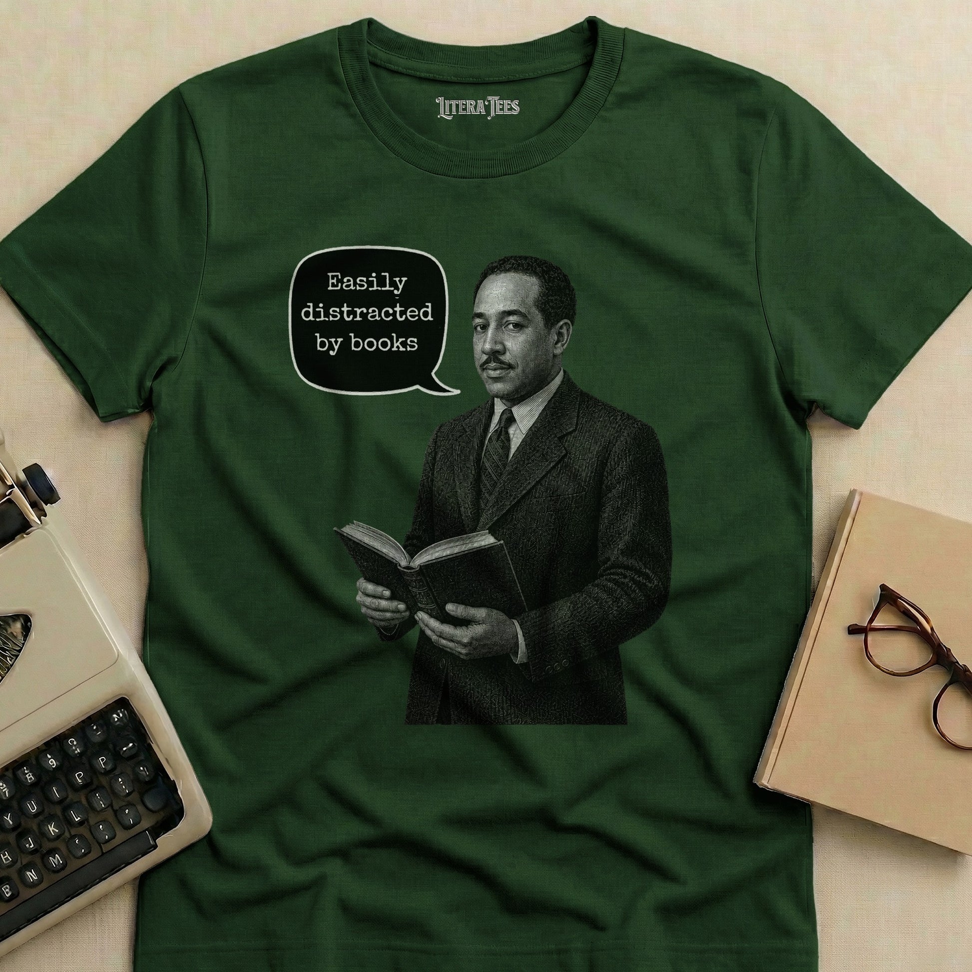 Green t-shirt with a graphic featuring a man reading a book and the text "Easily distracted by books".