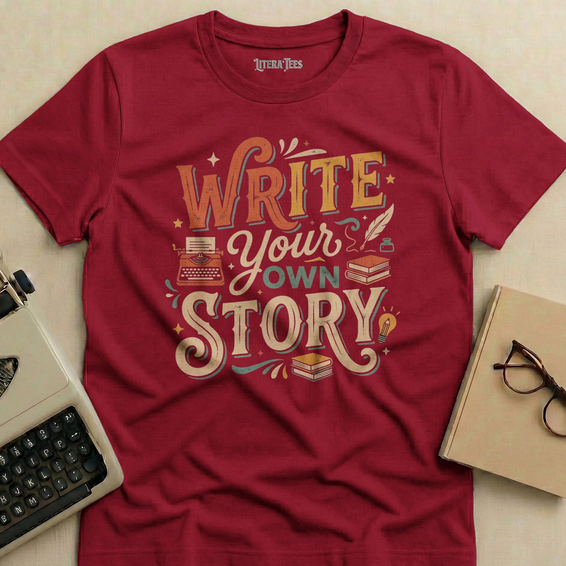 Maroon t-shirt with "Write Your Own Story" text and vintage typewriter graphic.